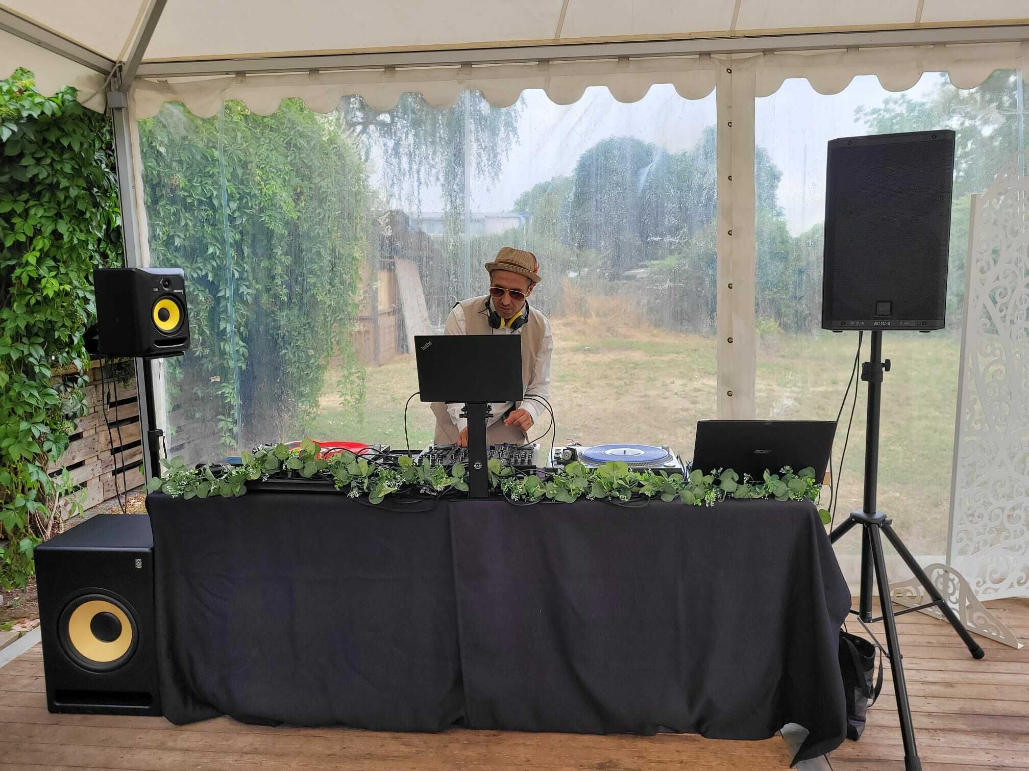DJ Maroof steht an seiner Musikanlage mit Mischpult, Plattenspieler und Laptop
