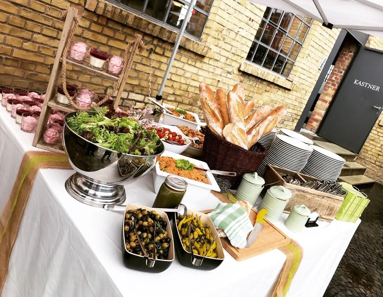 Bild zeigt mehrere Salate und Weißbrot, sowie Nachtischgläser mit rötlicher Creme