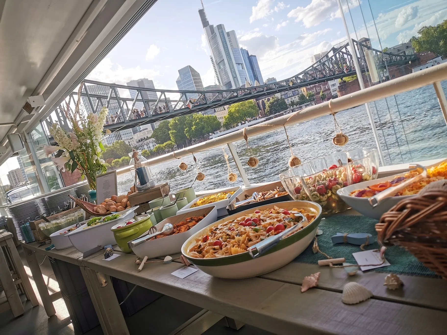 Bild zeigt ein Salatbufett mit verschieden Schüsseln und Schalen mit unterschiedlichen Salaten vor der Skxline von Frankfurt