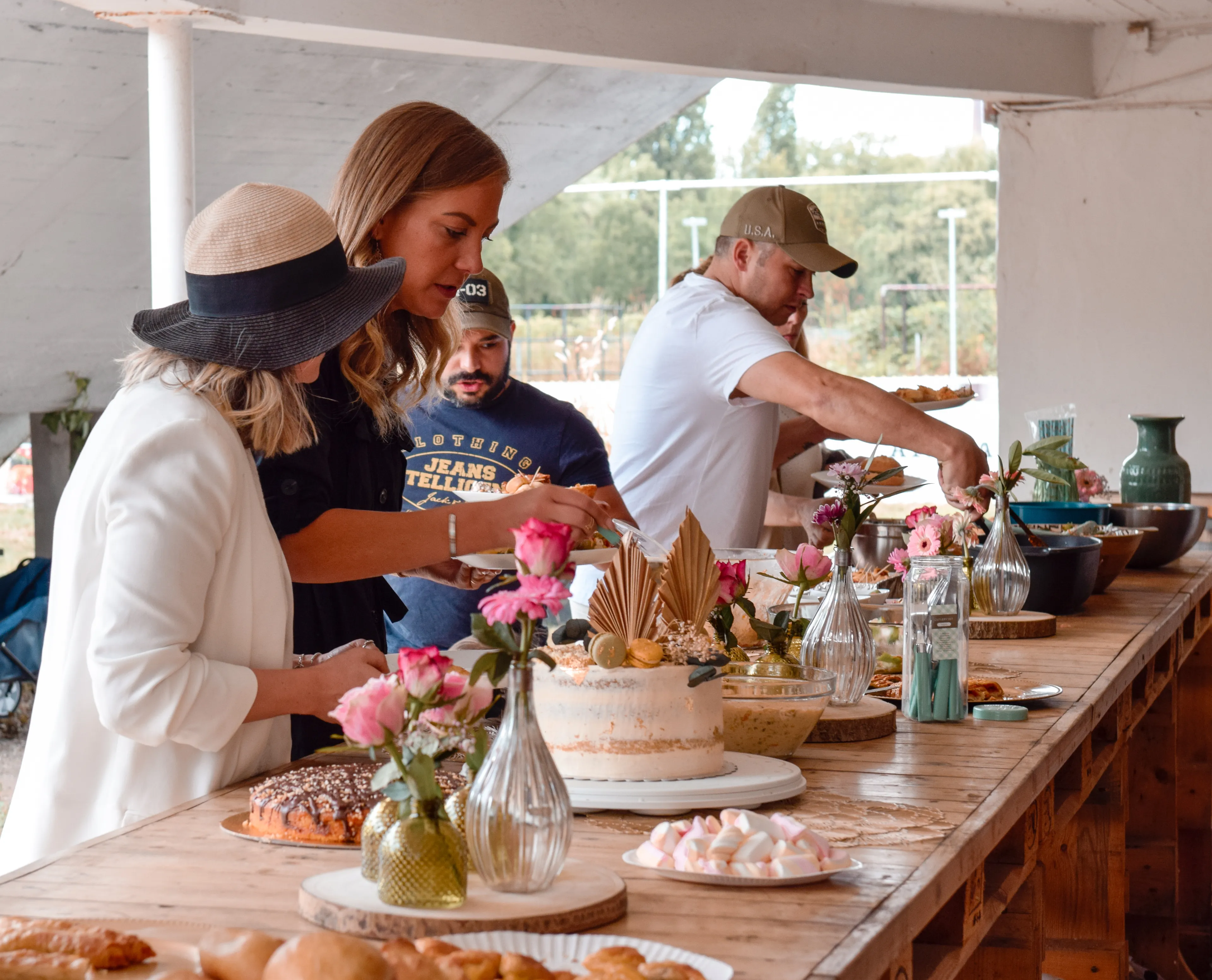 Auf dem Bild sind Gäste zu sehen, die sich am aufgebauten Bufett bedienen