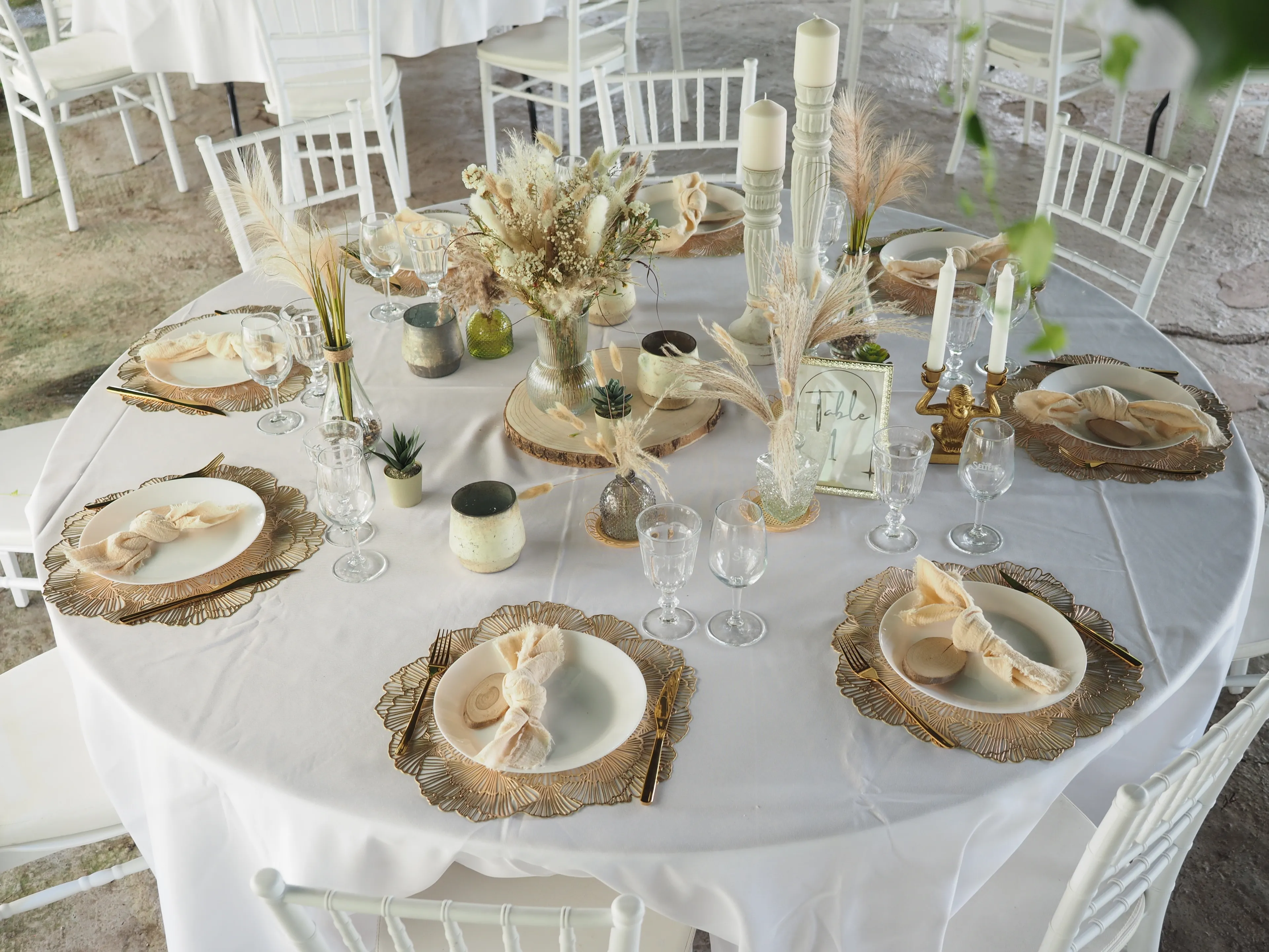 Bild zeigt die Eindeckung des Boho Vintage Deluxe-Tisches mit einer Deko aus Blumenarrangement und Kerzen